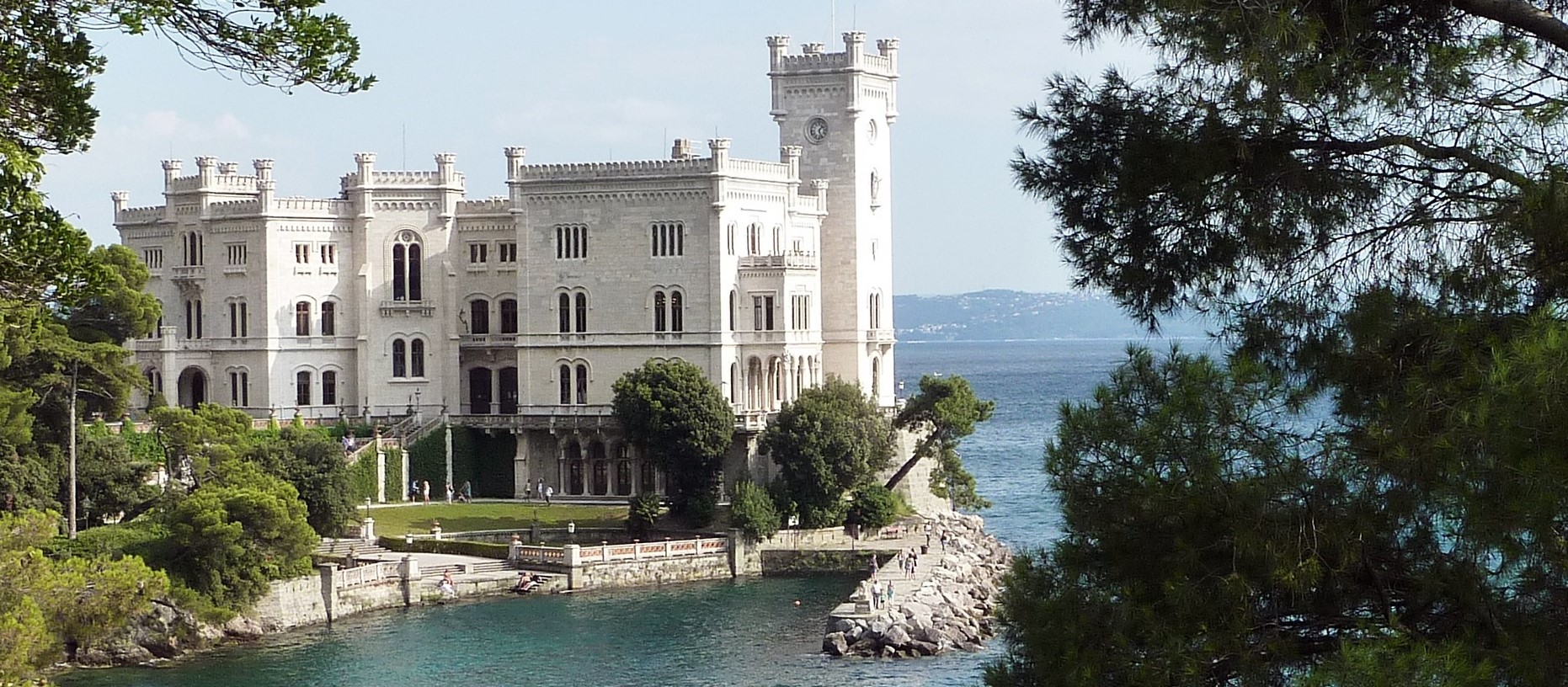 Miramare Castle in northeastern Italy, a white castle surrounded by trees overlooking the sea. 